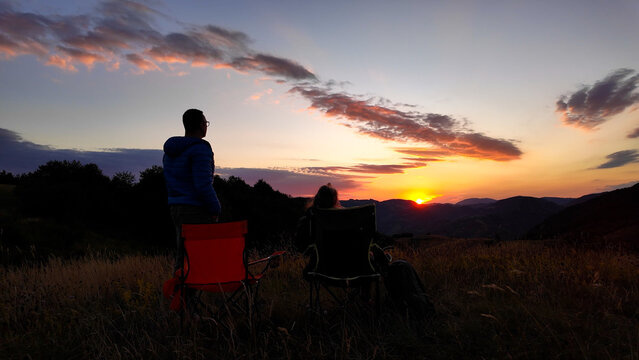 Man and woman looking at the sunset over the distant mountains.