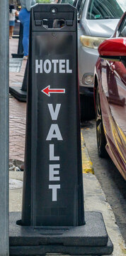 Vertical Image of Hotel Valet Sign on the Sidewalk Next to Parked Cars in Downtown New Orleans, LA, USA
