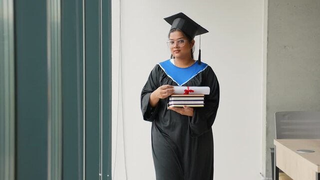 Proud female graduate student holding books and diploma