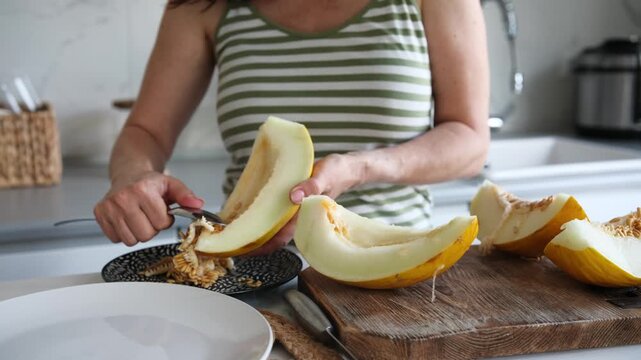 Woman Cutting Melon Into Pieces In The Kitchen Close-Up