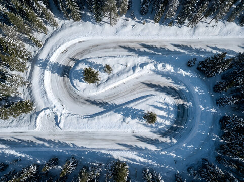 Drone shot of winding switchback road in snow covered forest