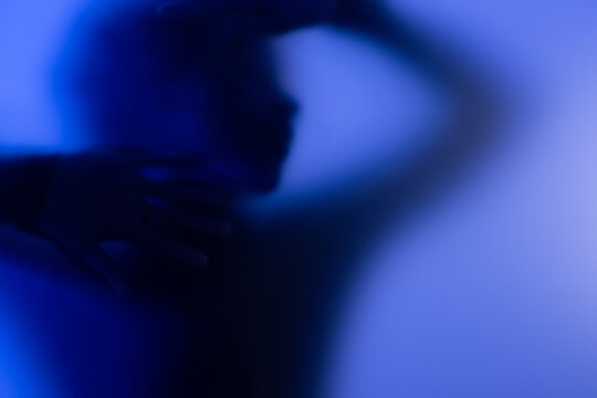Young black woman behind matte glass. Concept of mental issues and depression trap. 