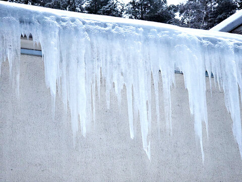 Large icicles hanging from the roof of a brick building.