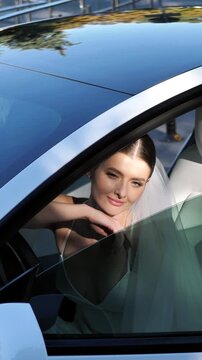 Beautiful elegant bride sitting in a car and smiling gently close up.
