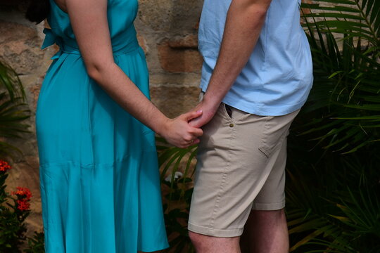 romantic young couple holding hands closeup outdoors, loving man and woman holding hands midsection detailed shot, couple holding hands tender gesture concept of love and affection, lovers holding han