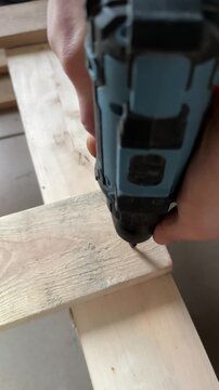 The cordless screwdriver drives the screw into the board. . High quality 4k footage