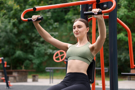 Woman exercising on chest press machine at outdoor gym