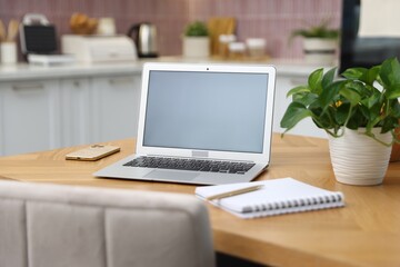 Fototapeta premium Workplace with laptop, smartphone, stationery and houseplant on wooden table indoors