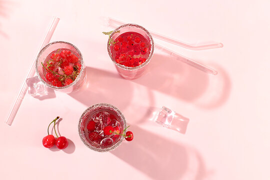 Modern still life with berry juice, raspberries, cherries, red currants, and ice on an elegant kitchen table, casting long, sharp shadows. The concept is a minimal detox diet, summer vitamin drinks