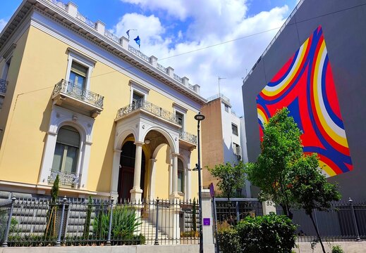 Exterior view of the historic 19th-century Deligiorgis Mansion beside the geometric street art of Nassos Daphnis in Kolonaki, Athens, Greece.