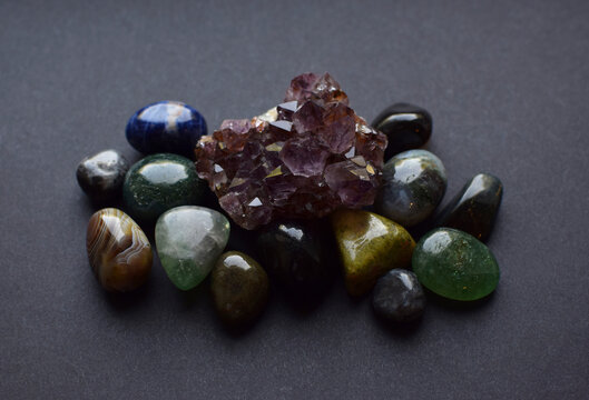 Amethyst quartz druse and round agate and fluorite stones on a gray background. Semi-precious natural stones for magic and meditation. Healing crystals.