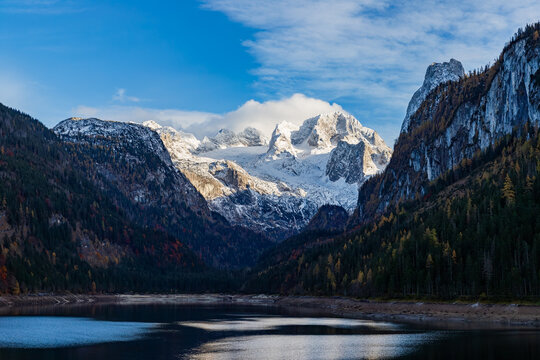 The Gosau lake (Upper Gosausee) surrounded by tall mountains and forested hills with Dachstein glacier in background. Austria 