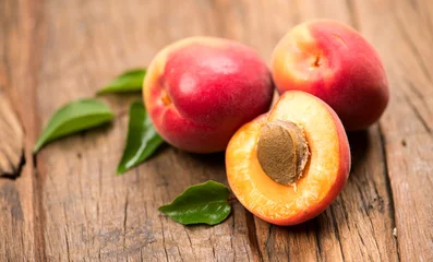Apricots. Close-up of fresh organic apricot fruits on a rustic wooden table. Fresh bio apricot with leaves closeup, top view.  © Subbotina Anna