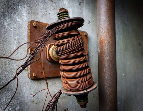rusty vintage porcelain electrical insulator with twisted metal wires on concrete wall
