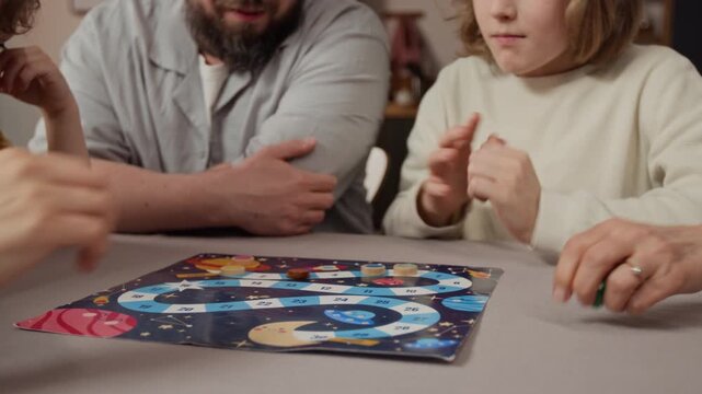 Caucasian family playing board game at table, child rolling dice and moving game piece. Footage for family leisure, home entertainment, and toy advertising campaigns