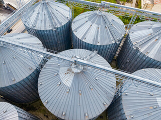 Rows of large metal silos used for grain storage in an agricultural area during daylight © DSMT