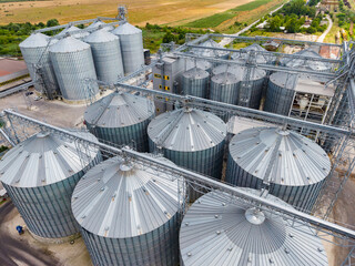 Grain storage facility with silos and machinery in a rural area during daytime © DSMT