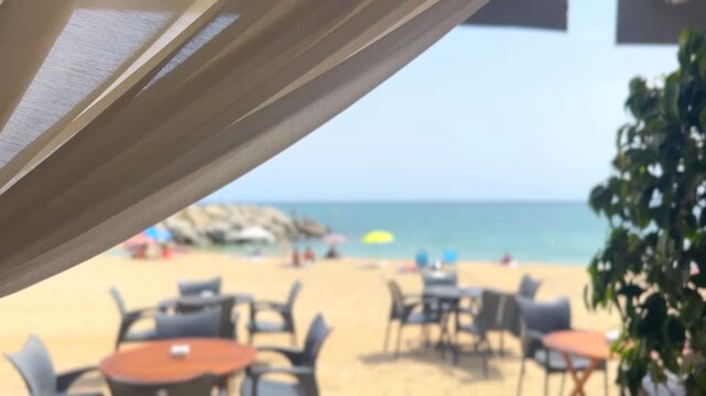 Cafe on the beach, seaside outdoor beach restaurant blurred background, terrace view, chairs, sun umbrellas, tables on beautiful Mediterranean public sandy beach in summer waiting for tourists for din
