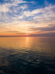 Obraz premium Sunset over the ocean with clouds and calm water in the evening sky near the coastline