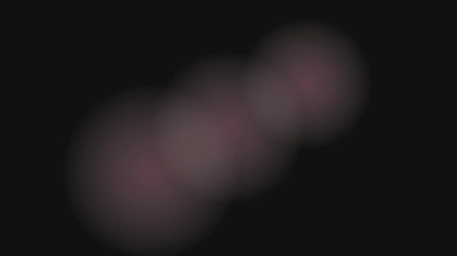 Abstract moving bokeh light shapes softly glow on a dark background