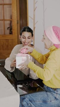 Mother with cancer and daughter sharing a loving gift together