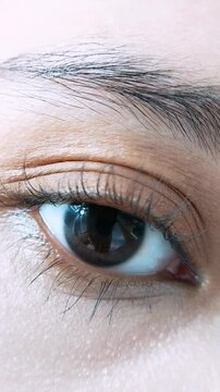 One eye blinking while looking at camera from close up. Eyebrow, lashes, and eye visible for face beauty theme. Natural eye movement concept.