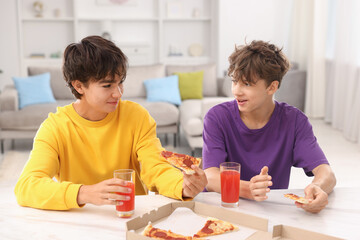 Obraz premium Teenage brothers eating pizza and drinking juice at white marble countertop at home