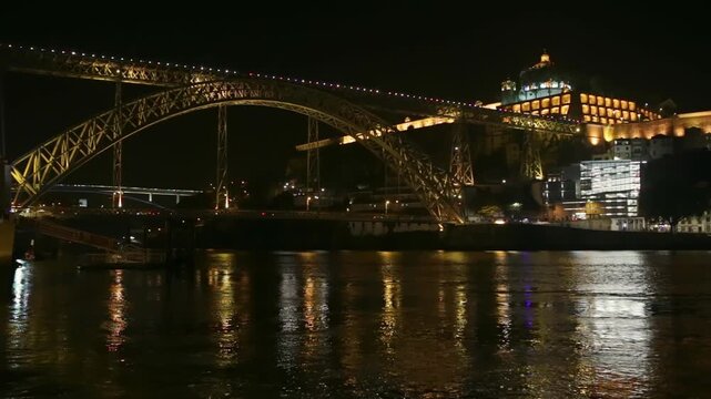 Magnificent night view of illuminated dom luis i bridge and serra do pilar monastery, with their lights reflecting on the flowing waters of the douro river in porto, portugal