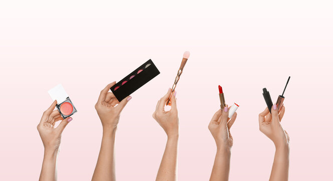 Women holding different cosmetics and makeup brush on light background, closeup. Banner design
