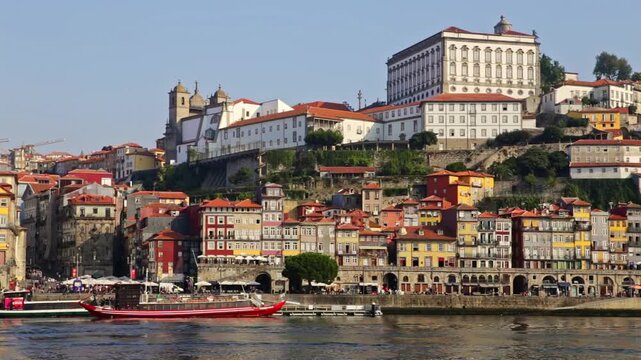 Historical colorful buildings of the ribeira district lining the douro river in porto, portugal, with a traditional rabelo boat moored at the riverbank on a beautiful sunny day