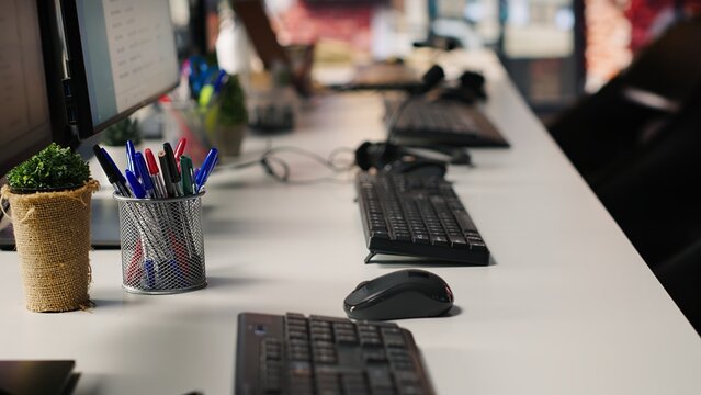 Customer service management software appears on computer monitors beside audio headsets in an empty call center prepared for client support.