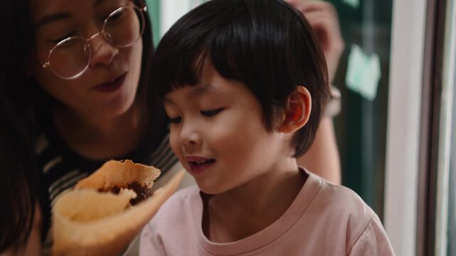 Mother and son happily eating a sweet crepe at a local food market