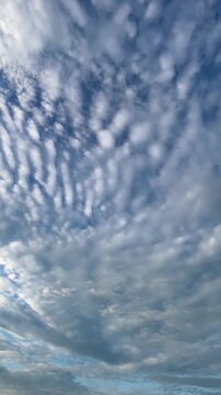 Vertical tracking shot of textured ripple altocumulus clouds in a blue sky.