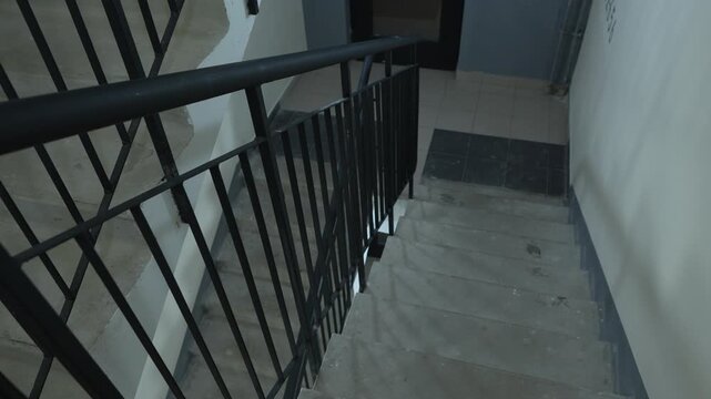 Empty stairwell inside a modern residential building with black metal railing, concrete steps and minimalist architectural design
