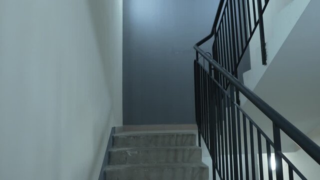 Concrete staircase with black metal railing and white walls showing minimalist architecture and interior space design