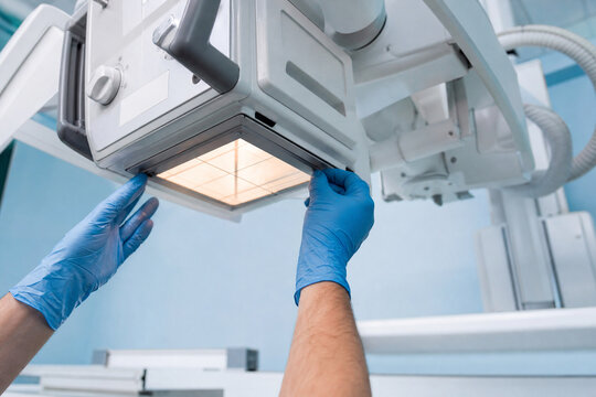 Hands in blue gloves checking collimator light field with crosshair under x-ray tube. Quality control and beam alignment testing of radiography equipment. Generative AI.