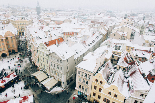 Winter in town. A breathtaking aerial view of a snow-covered city, showcasing charming rooftops and lively streets filled with people.