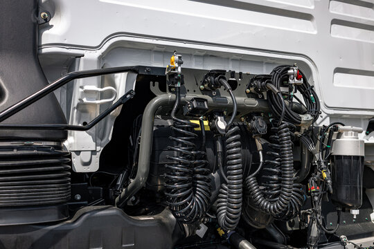 Semi truck cabin back wall with coiled air hoses and lines. Commercial cargo transport vehicle trailer connection coupling panel section with modern heavy duty tractor engineering details.