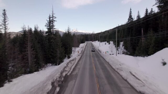 Aerial drone view of winding mountain highway through snowy Coast Mountains near Whistler, British Columbia