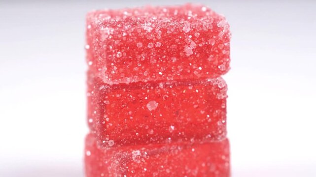 Stack of three red gelatin cubes with crystalline texture arranged on white surface.