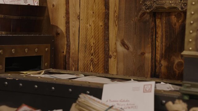 Christmas letters and envelopes move along a rustic mail sorting belt in a workshop with wooden wall paneling and holiday decor