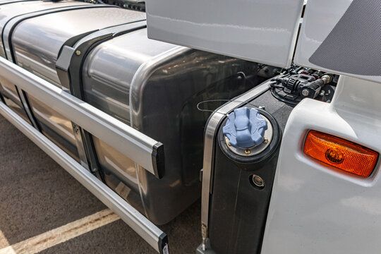 Semi truck fuel and adblue tanks behind side protective barrier. Commercial vehicle chassis component section with aluminum reservoirs and heavy duty industrial transport vehicle details.