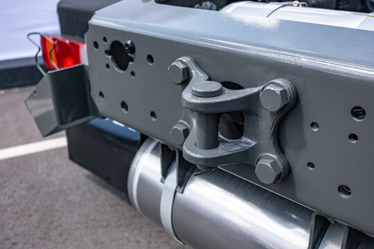 Semi truck chassis rear crossmember with towing hitch pin. Commercial cargo transport vehicle tractor frame section with aluminum air receiver tank and heavy duty engineering details view.