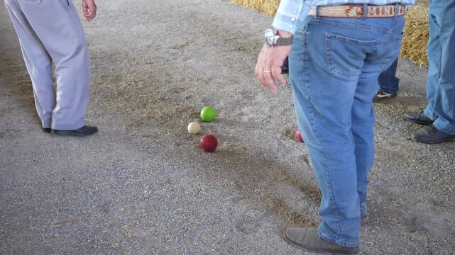 Close up  shot of a bocce ball court focused on the jack as unrecognizable players compete in backgroundt. Outdoor precision sport, recreation, strategy, friendly competition and leisure