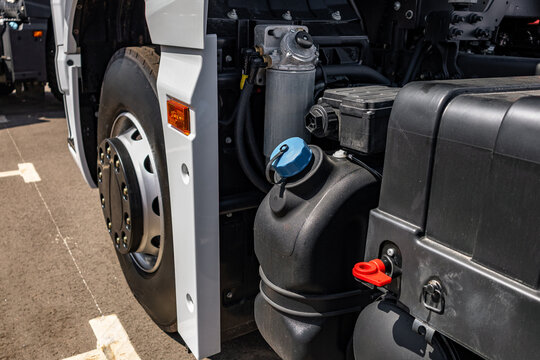Semi truck adblue def tank with blue cap on chassis frame. Commercial heavy duty transport vehicle diesel exhaust fluid plastic reservoir with fuel tank engineering technical details.