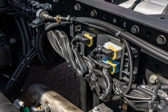 Semi truck chassis electronic control unit with wiring harness. Modern commercial vehicle tractor electrical distribution module on frame and long haul transport technical engineering details.