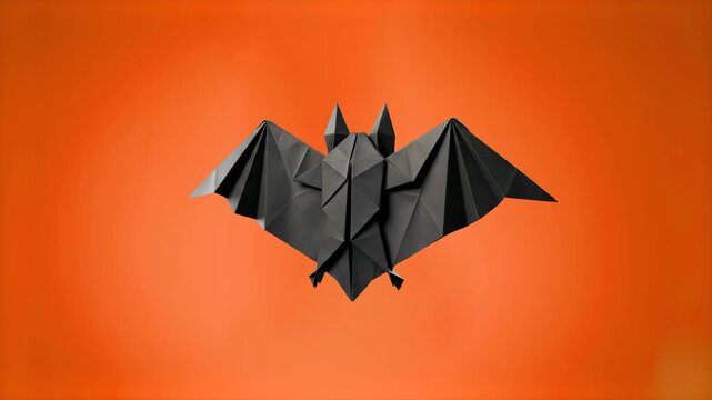 Black low poly origami bat with outstretched wings hovering over a warm orange Halloween background. Ideal for October holiday decorations, party banners, spooky concepts, and paper craft designs.
