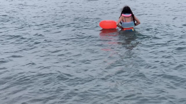 Cute Little Girl Enjoying the Beach with Colorful Inflatable Rings