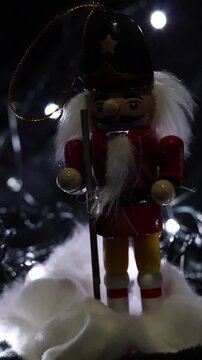 Una toma de cerca de un cascanueces o soldadito con luz en un fondo negro. Video vertical 