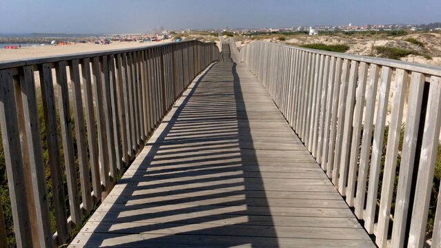First person perspective of walking on a wooden boardwalk toward a sandy beach in Paramos Portugal
